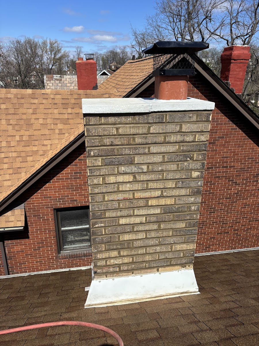 Rebuilt brick chimney with new cap and flashing on a rooftop